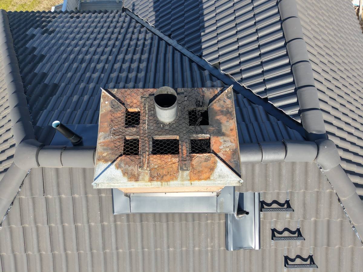 Close-up drone photo of a rusted chimney vent cap during a roof inspection