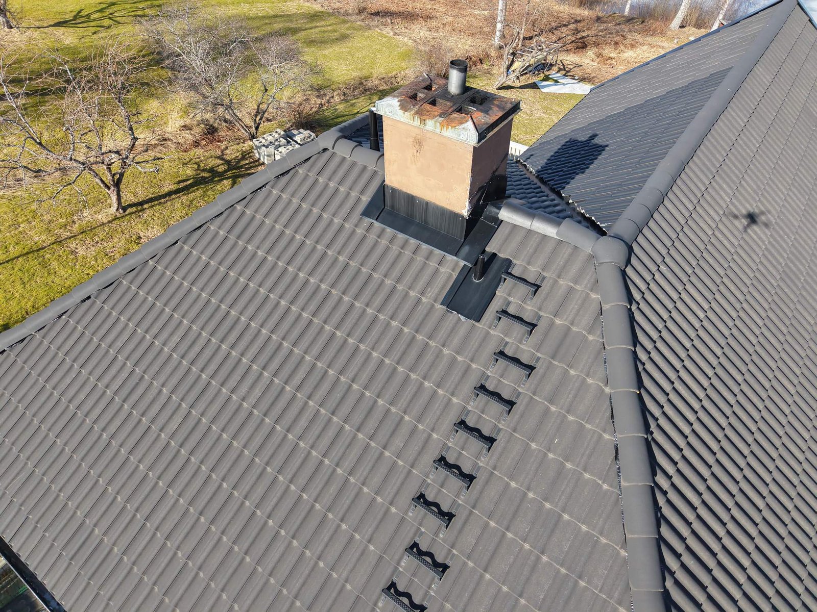 Aerial drone photo of a tiled roof, chimney and surrounding property